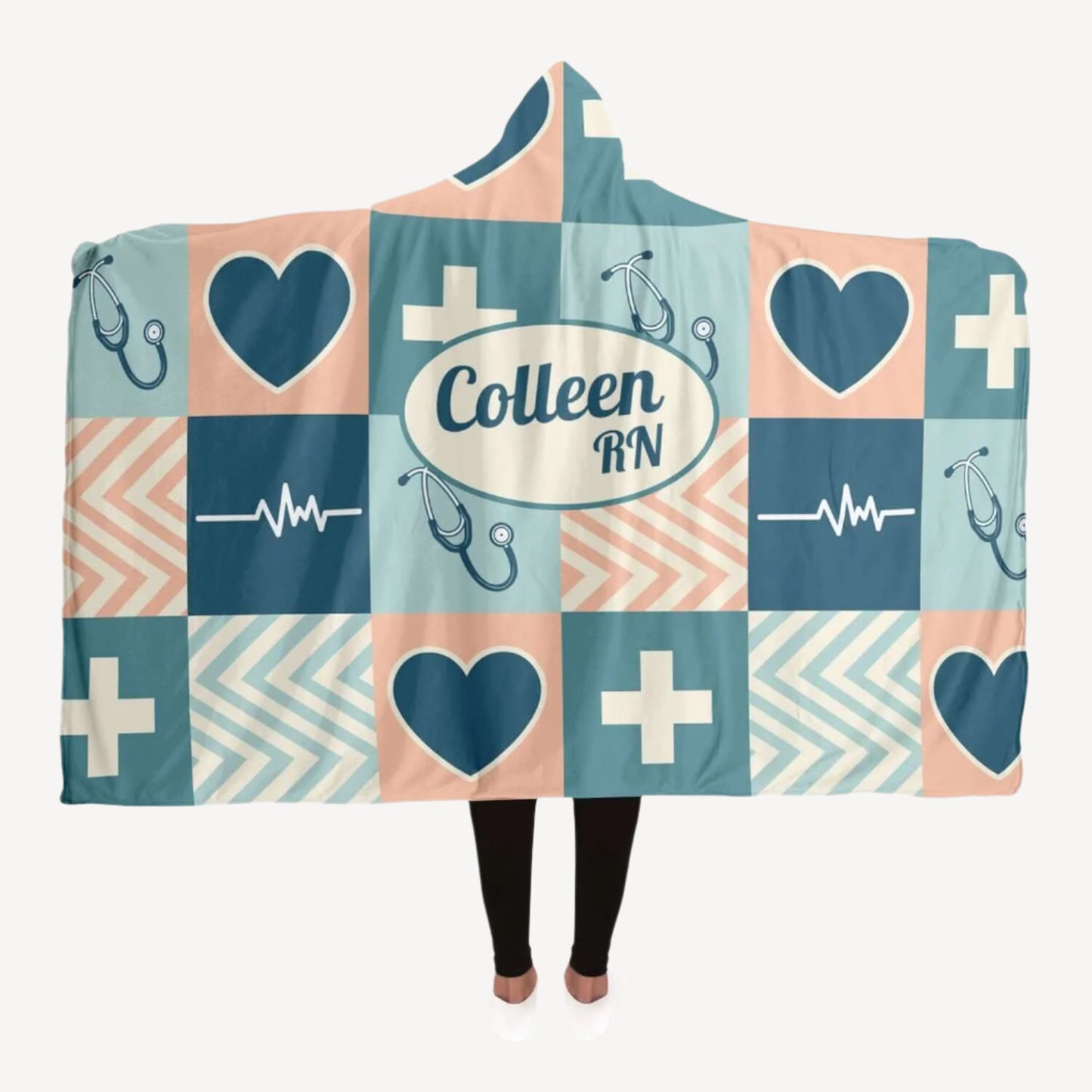 A person wearing a Personalized Nurses Hooded Blanket featuring a patchwork design. The blanket displays teal, navy, and peach squares with symbols such as hearts, crosses, stethoscopes, and EKG lines. Perfect as a nurse gift offering comfort and relaxation, it has "Colleen RN" printed in a central oval.