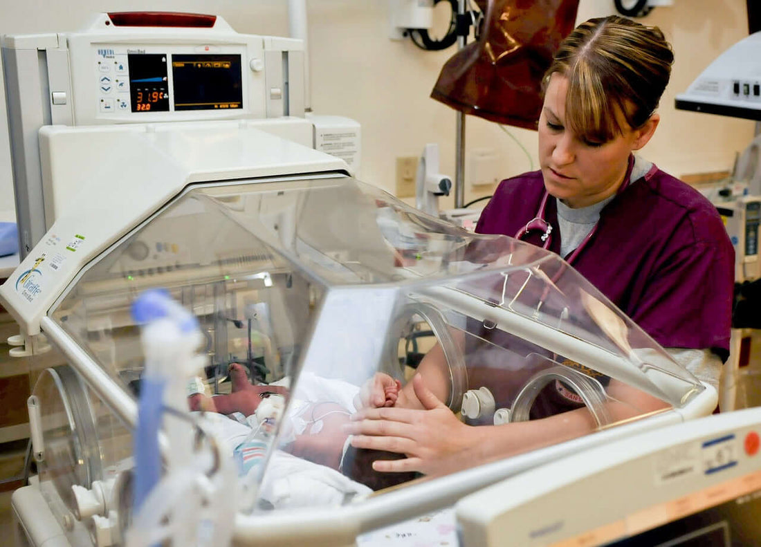 Unrecognizable nurse caressing a newborn baby in an incubator while he sleeps