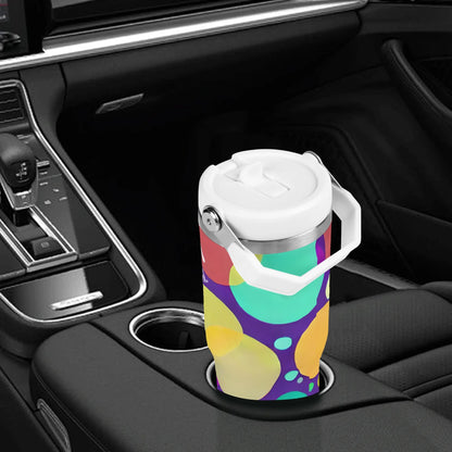 A 30oz Nurse Tumbler with Stylish Circle Design – Perfect for Busy Nurses, featuring a white lid and handle, is placed in a car cup holder. The tumbler showcases a vibrant pattern of large, overlapping circles in yellow, green, blue, and purple. The car interior boasts black leather seats and a sleek dashboard.