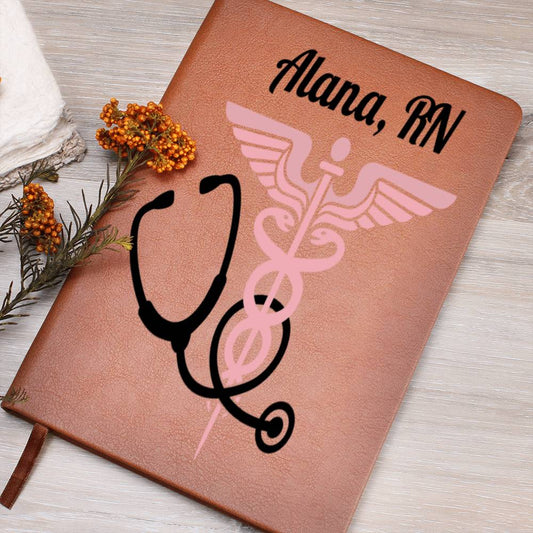 A Custom Medical Journal: Personalized Notebook for Doctors & Nurses - Leather with "Alana, RN" written at the top in black cursive. Below, there's a pink caduceus symbol intertwined with a black stethoscope. This unique gift is placed on a gray wooden surface with orange berries and greenery beside it.