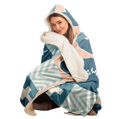 A person wearing a Personalized Nurses Hooded Blanket sits comfortably, smiling at the camera. The inside of the blanket is white and fluffy, radiating comfort and relaxation. The individual appears to be cozy and content, making it an ideal nurse gift.